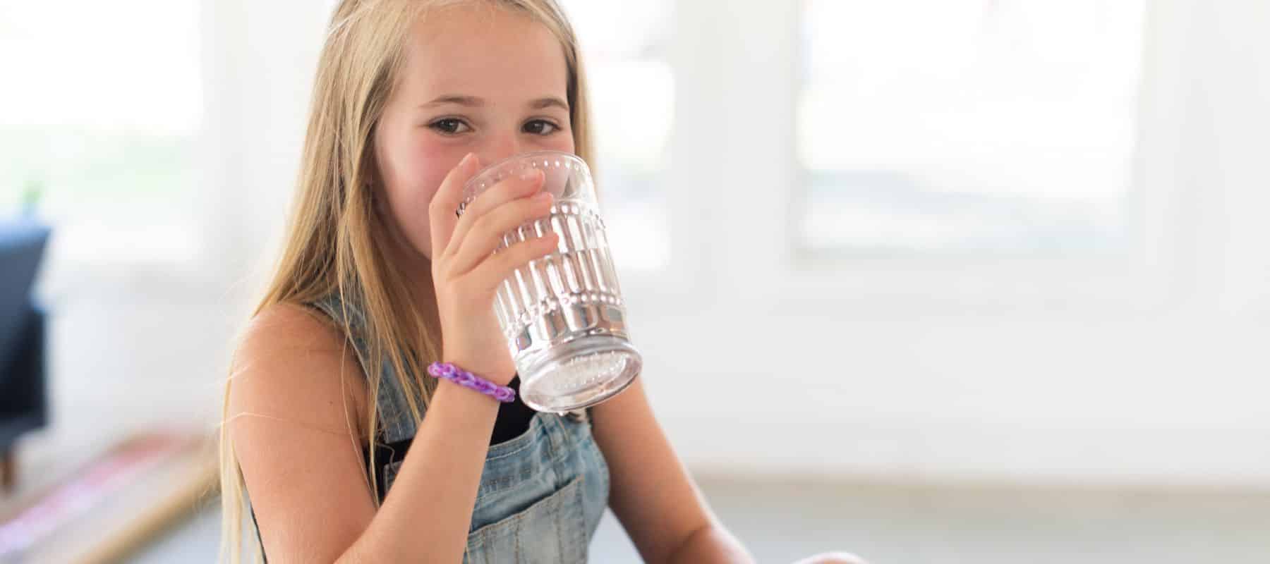 child drinking water out of a glass