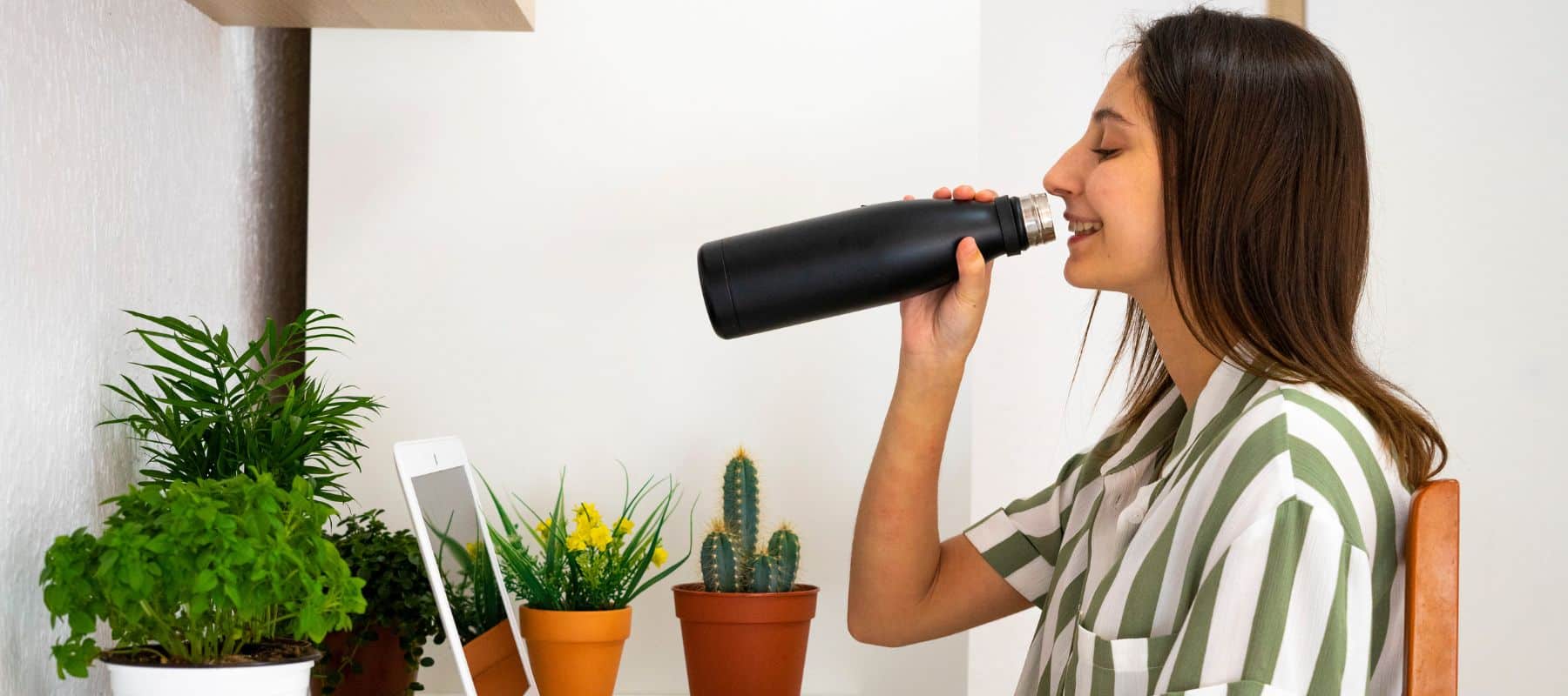 Woman drinking water out of a stainless steel mug