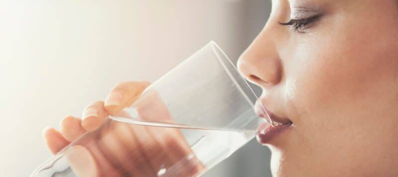 woman drinking from a glass of softened water