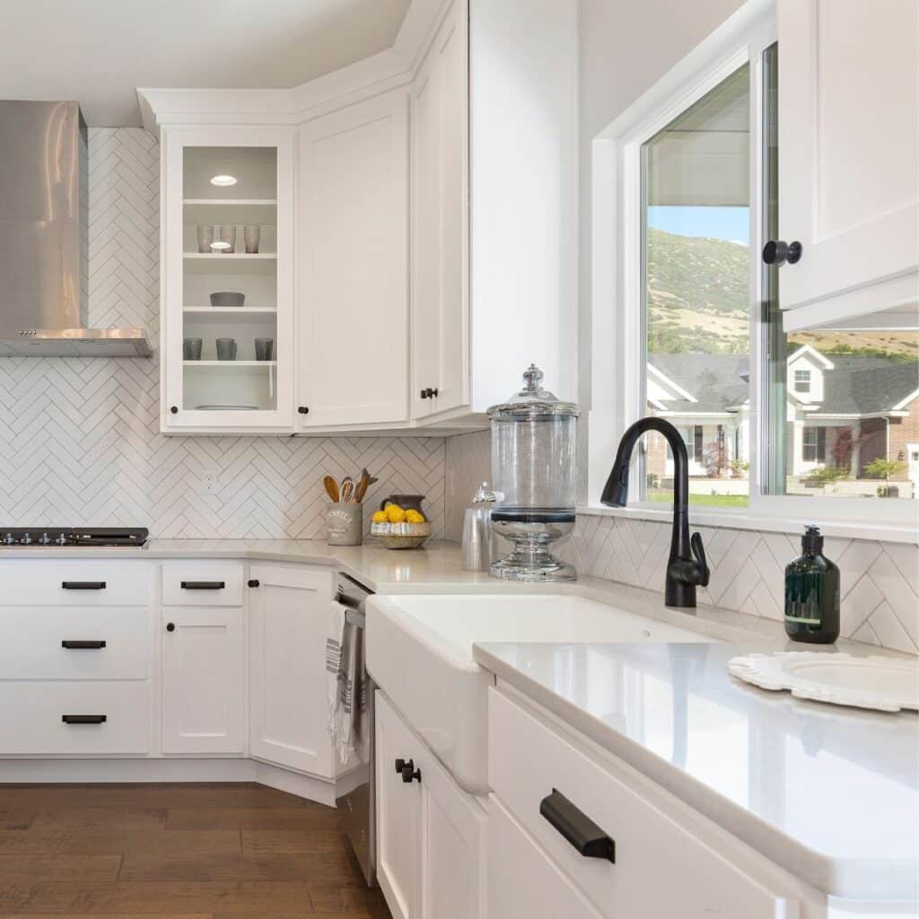 all white kitchen with things on the counter and showing the sink with a window on top of it