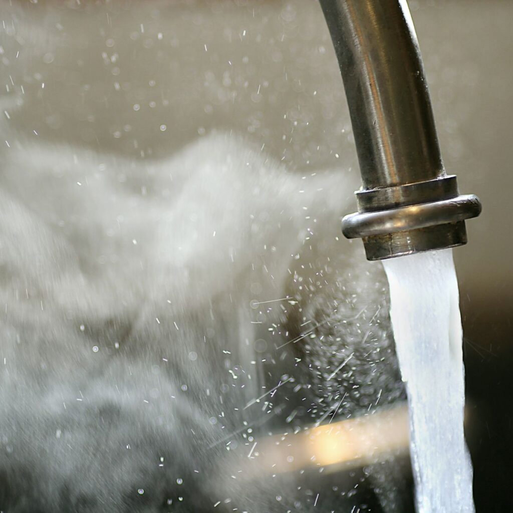 water running out of a faucet with steaming hot water